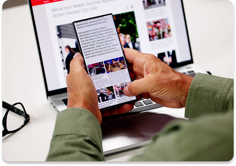 Person browsing on smartphone and laptop simultaneously.